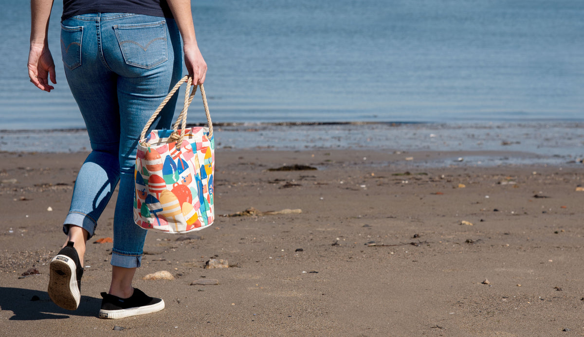 beach coastline at low tide as person strolls with a buoy-pattern tote bag