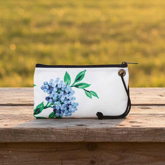 White wristlet with floral design on a wooden surface with a field background