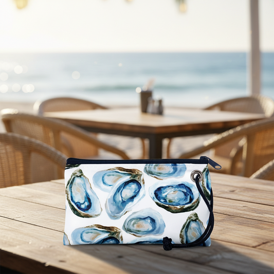 oyster wristlet on a cafe table by the beach