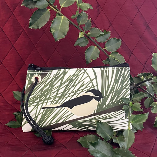 Sea Bags Maine Chickadee Wristlet made of recycled sailcloth, featuring a chickadee perched on pine needles with a black cord wrist strap.