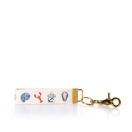 Keychain with lobster, crab, and shell designs on a white background