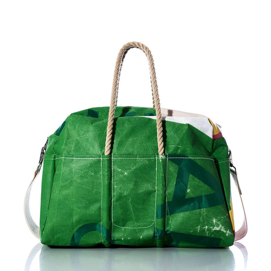 A Sea Bags Vintage Multicolor Weekender, featuring sturdy hemp handles, a white shoulder strap, and visible creases, is displayed on a reflective surface. by Sea Bags