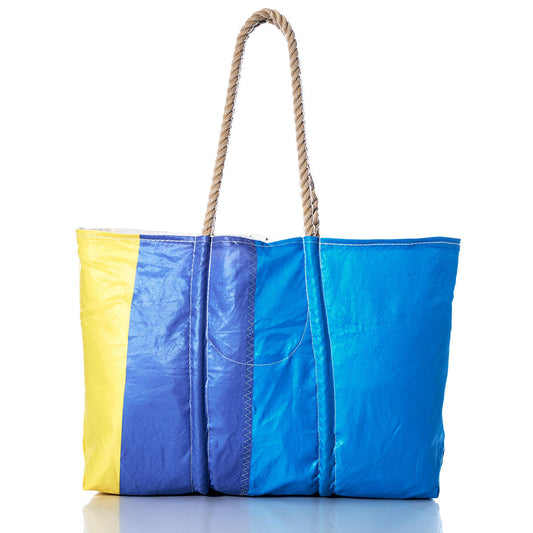 Sea Bags Vintage Blue and Yellow Large Tote is pictured on a white background, featuring bold yellow, blue, and cyan vertical stripes, hand-spliced rope handles, and a small front pocket. This Maine handcrafted bag is ideal for everyday adventures. by Sea Bags