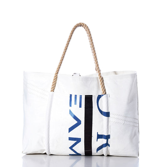 The Sea Bags Vintage Black Trident Wharf Tote is a large white recycled sail tote bag featuring bold blue and black lettering, sturdy rope handles, and visible stitching. Handcrafted to reflect the nautical spirit of Portland, Maine, this tote stands upright on a reflective surface against a white background. by Sea Bags