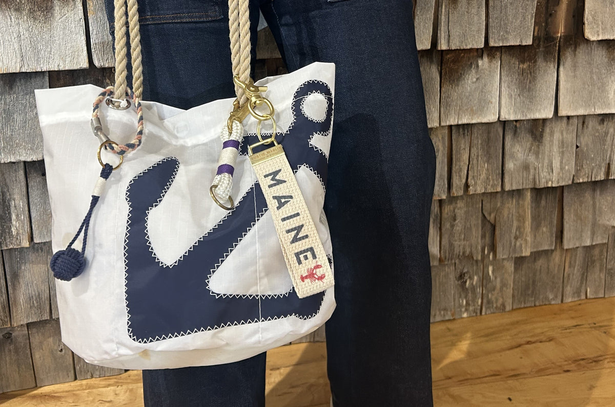 keychains and tote bag charms attached to a yellow stripe recycled tote bag, on a wharf