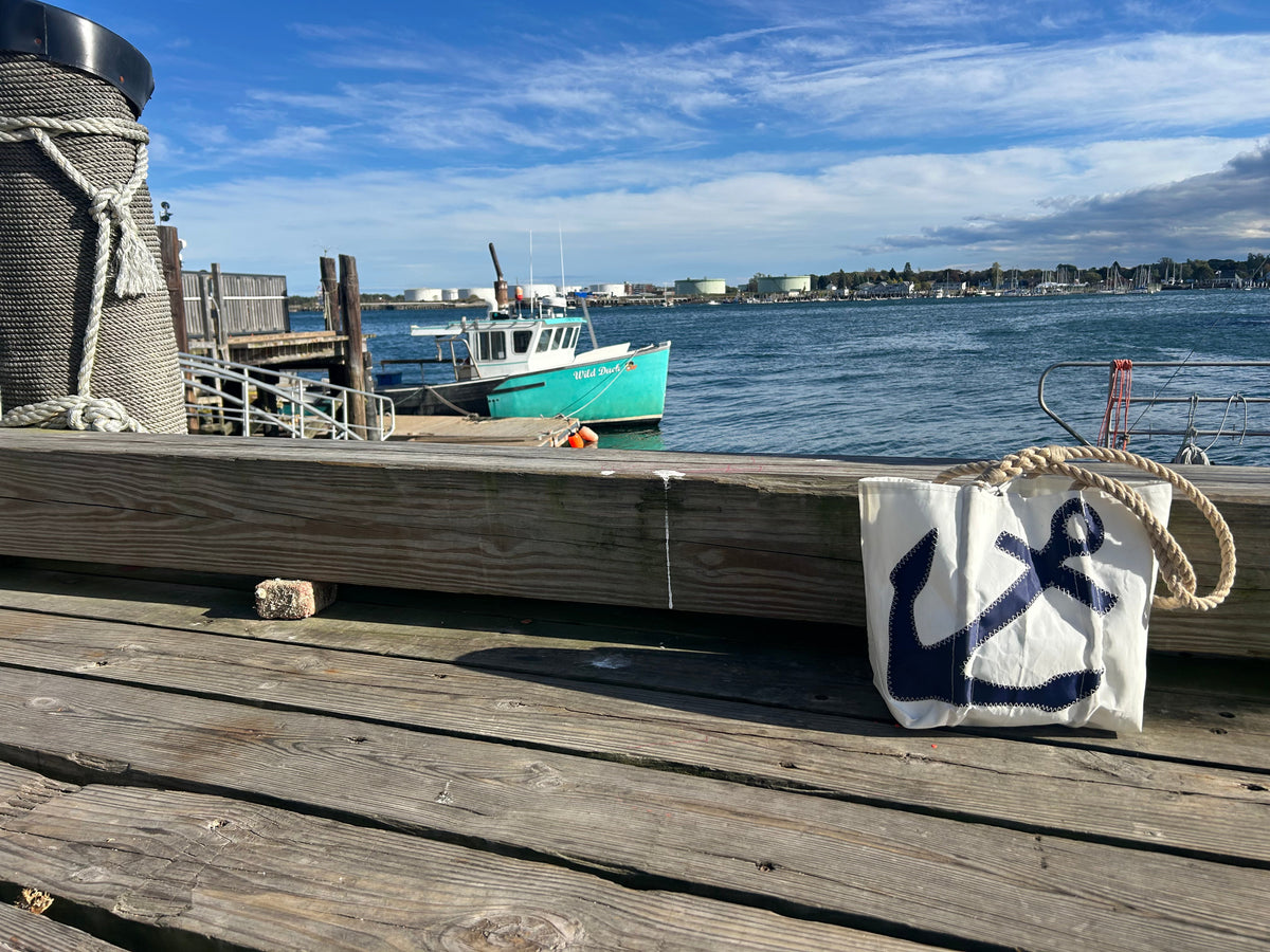 Recycled sail cloth anchor tote on wharf pier overlooking fishing harbor