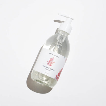 Mermaid Kisses Eco-Friendly Liquid Soap by Shore Soap Co is presented in a pump bottle labeled “Shore Soap Co. Mermaid Kisses,” featuring a red coral illustration and displayed on a white background. This gentle formula, made with natural ingredients, is perfect for sensitive skin.