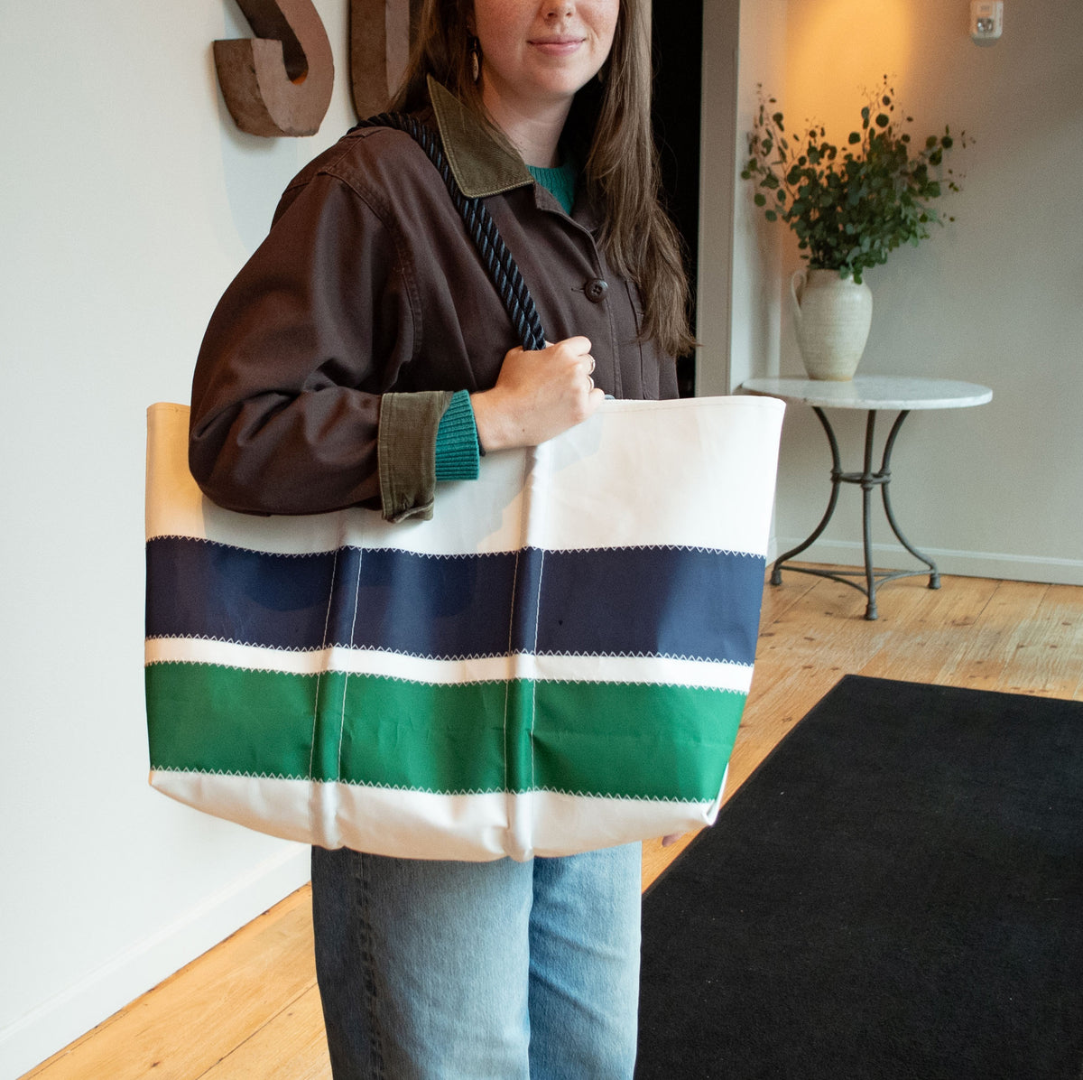 A person carrying a large, white Navy  Green Stripe Large Tote with nautical stripes and marine rope handles.