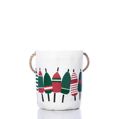 The Sea Bags Holiday Buoys Bucket Bag features a white recycled sail cloth design, adorned on the front with colorful red, green, and striped buoy patterns. Finished with sturdy rope handles, this sustainable bag adds a coastal holiday touch to your décor. by Sea Bags