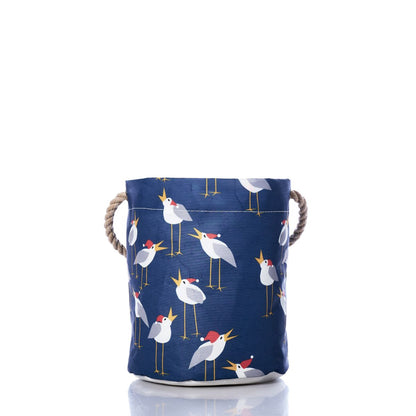 Bring festive, coastal charm to your home with the Caroling Gulls Bucket Bag by Sea Bags. Made from recycled sail cloth, this navy blue fabric basket features rope handles and a cheerful pattern of white birds with red crests—blending eco-friendly design with holiday inspiration. by Sea Bags