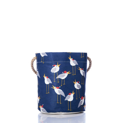 Bring a whimsical touch to your coastal Christmas decor with the Sea Bags Caroling Gulls Bucket Bag—a navy blue fabric storage bin featuring sturdy rope handles and a charming repeating pattern of white birds with orange beaks and feet, standing on thin legs. by Sea Bags