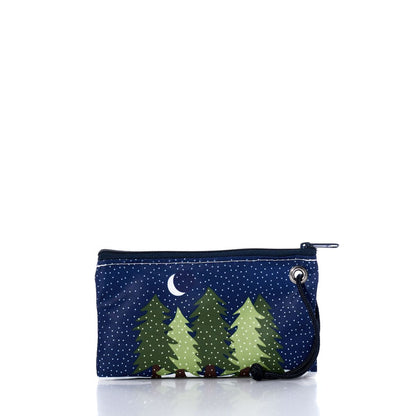 The Sea Bags Midnight Snow Wristlet is a recycled sailcloth pouch in navy, featuring a print of green pine trees, a crescent moon, and white snow-like dots, finished with a black cord loop—making it a charming winter accessory. by Sea Bags
