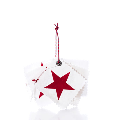 A set of five white square Sea Bags Sail Cloth Gift Tags, each adorned with a red star and crafted from sustainable recycled sail material, are stacked and tied together with a red and white string against a white background. by Sea Bags