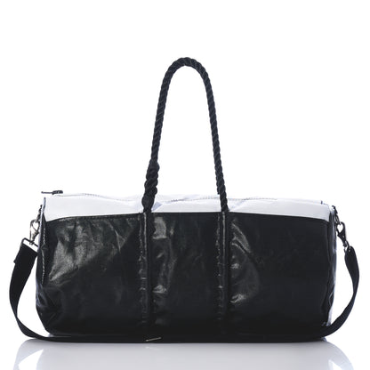 Introducing the Black Dragon Duffel by Sea Bags—a black and white travel duffel bag made from recycled sail cloth, designed with rope handles and a detachable shoulder strap. Shown on a reflective surface against a white background, this water-resistant bag combines style and durability, making it the perfect companion for your next adventure. by Sea Bags