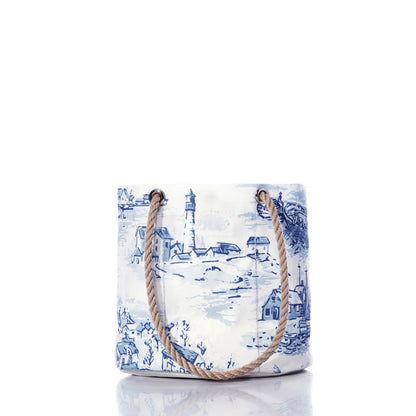 The Sea Bags Maine Fishing Village Essential Handbag is a white and blue canvas nautical bag, crafted from recycled sail cloth and adorned with charming illustrations of a lighthouse and coastal Maine scenery, featuring sturdy rope handles—all presented on a white background. by Sea Bags