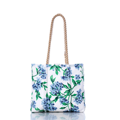 Sea Bags’ Blueberry Print Handbag features a blue and green floral pattern inspired by Maine blueberries, crafted from recycled sail cloth with two twisted rope handles, and shown against a white background. by Sea Bags
