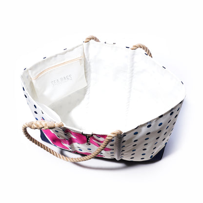 Introducing the Fuchsia Anchor  Summer Dots Ogunquit Beach Tote by Sea Bags, crafted from recycled sail cloth with a vibrant mix of white and blue polka-dot canvas, sturdy rope handles, and a fuchsia-patterned side. This stylish tote includes an interior pocket adorned with the Sea Bags logo, all showcased against a plain white background. by Sea Bags