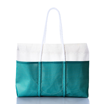 The Ocean Teal Beachcomber Tote by Sea Bags is displayed against a white background, featuring recycled sail material in teal and white, rope handles, three exterior pockets, and a reflective underside. This sand-proof beach bag seamlessly blends style with functionality, making it the ideal companion for your seaside adventures. by Sea Bags