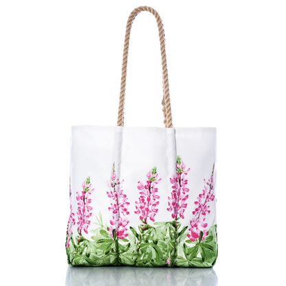 Introducing the Pink Lupine Medium Tote by Sea Bags—a sustainable everyday bag adorned with a pink and green wildflower print, inspired by the beauty of Maine lupines. Featuring two sturdy rope handles, this tote is displayed on a white background. by Sea Bags
