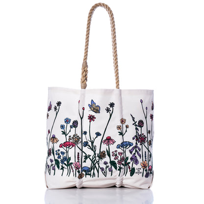 Sea Bags Life is Good Wildflowers Medium Tote, handcrafted in Maine from recycled sail bag materials, features rope handles and a vibrant wildflower and butterfly print along the bottom half, shown on a white background. by Sea Bags