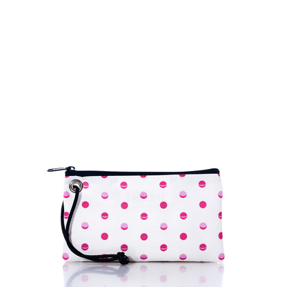 The Sea Bags Flip Side Summer Dots Wristlet is a white rectangular pouch adorned with playful pink and red polka dots. It features a secure zippered closure and a black cord wrist strap attached to a metal grommet on the side, making it a stylish and practical travel accessory. The pouch is shown isolated on a white background. by Sea Bags