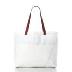 Sea Bags’ Large Market Tote, crafted from white recycled sail with brown leather handles, features an exterior pocket and visible zigzag stitching detail, shown against a plain white background. by Sea Bags