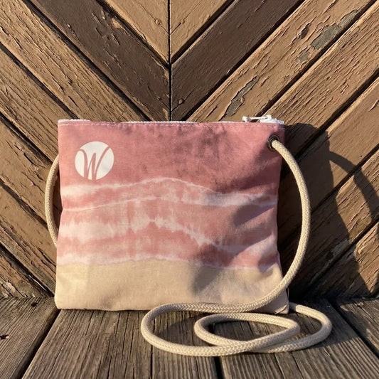 Shoreline Blush Slim Crossbody bag in a pink and tan tie-dye pattern, featuring a white logo and a rope shoulder strap for hands-free convenience.