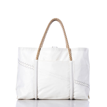 The U.S. Yacht Ensign Wharf Tote by Sea Bags is a large white canvas bag with rope handles, zigzag stitching details, and an exterior front pocket, photographed against a white background. Inspired by nautical style and crafted from recycled sail cloth, this tote showcases sustainable craftsmanship in every detail. by Sea Bags