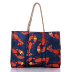 Introducing the Sea Bags Lobster Bake Large Tote: a navy blue maritime tote made from recycled sail cloth, adorned with red lobsters and yellow-striped lobster claws in a repeating pattern, and finished with classic rope handles—an ideal companion for any coastal adventure. by Sea Bags