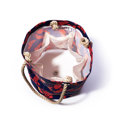 Top view of the Sea Bags Lobster Bake Beverage Bucket, an open, round recycled sail cloth bag featuring rope handles, a white interior lining, a lobster and floral exterior pattern, and multiple inner pockets. by Sea Bags