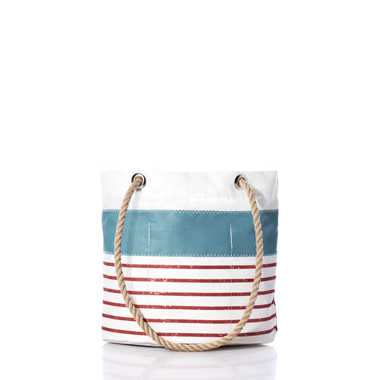 The Sea Bags Denim Blue-on-Red Mariner Stripe Essential Handbag features a white background adorned with bold red horizontal stripes and a denim blue accent stripe near the top, complemented by a sturdy rope handle. Crafted from recycled sail cloth, this lightweight and practical handbag is ideal for everyday use.