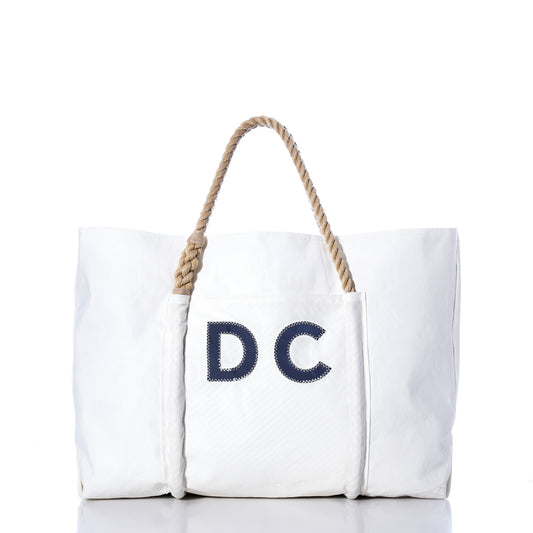 Sea Bags Custom Monogram Trolley Sleeve Tote—crafted from recycled sailcloth with a trolley sleeve, rope handles, and bold navy blue “DC” lettering on the front pocket; a stylish travel companion shown on a plain white background.