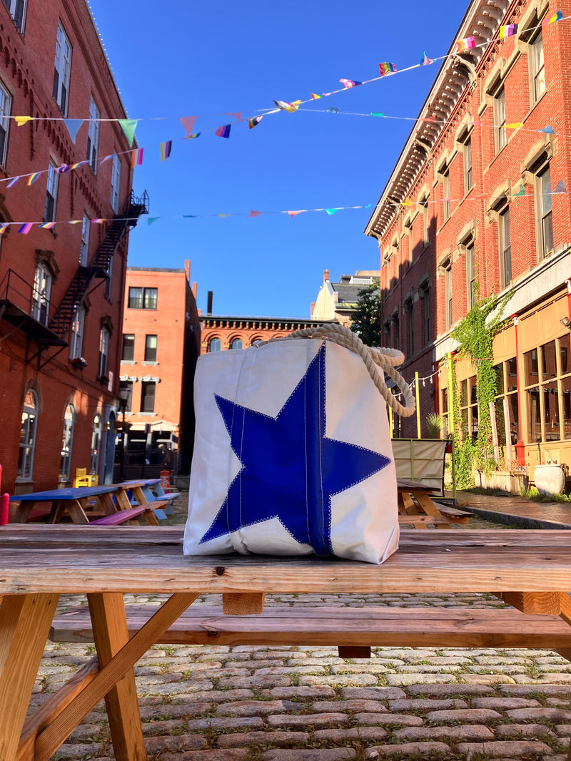 blue star medium tote in cobblestone street under a blue sky