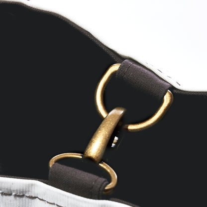 A brass lobster clasp connects two D-rings on a Heritage Ticonderoga Medium Tote made of vintage sail cloth.