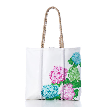 2026 Hope In Bloom Medium Tote with Clasp made of white sailcloth with rope handles, decorated with a print of pink, blue, and green hydrangea flowers.