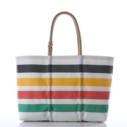 The Hudson Bay Stripe Large Tote by Sea Bags is a spacious white tote bag with sturdy rope handles, featuring classic American-inspired horizontal stripes in black, yellow, red, and green. Photographed against a white background, this roomy bag is perfect for carrying all your daily essentials. by Sea Bags