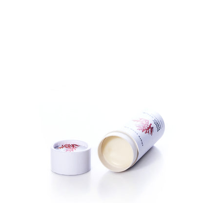 A cylindrical tube of Mermaid Kisses Eco-Friendly Body Balm lying on its side next to its removed lid.