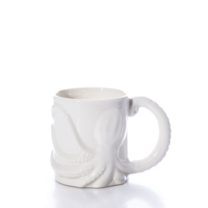 The White Octopus Mug by Batela USA Inc is a white ceramic mug with a raised octopus design, featuring one tentacle as the handle, and is shown against a plain white background. by Sea Bags