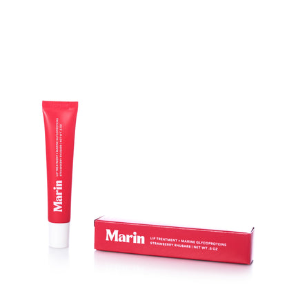 A red tube of Marin Lip Treatment - Strawberry Rhubarb standing next to its matching red rectangular box.