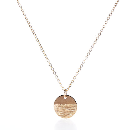The Pendant Necklace - Horizon Gold by Maine Yoga Jewelry features a fine gold chain and a round, textured gold pendant, beautifully photographed on a white background—an exquisite addition to any jewelry collection. by Sea Bags