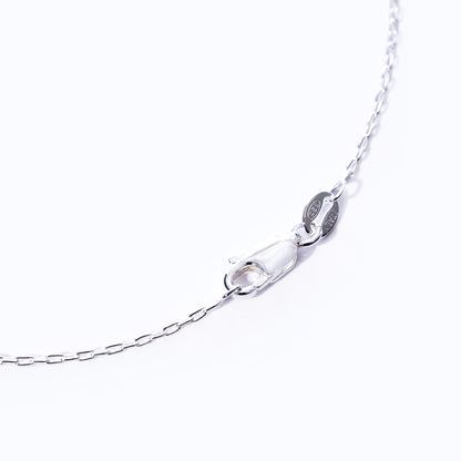 Close-up of the Pendant Necklace - Sand Dollar Silver by Maine Yoga Jewelry, featuring a silver chain with a lobster clasp and a small oval tag, displayed against a white background to highlight its sustainable craftsmanship inspired by the natural beauty of Maine. by Sea Bags