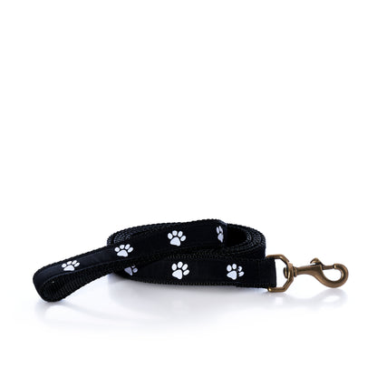 Black heavy-duty nylon Paw Print Dog Leash with a white paw print pattern and a brass-colored metal clip for adventurous pups.