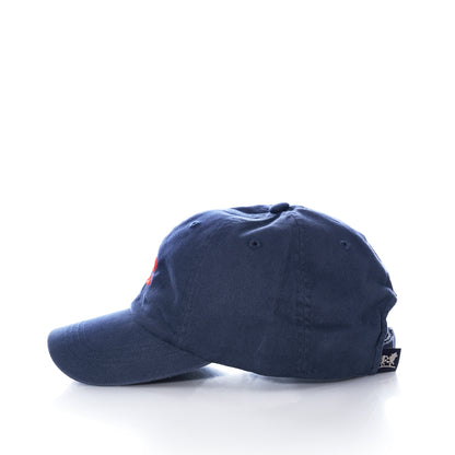 The Belted Cow Lobster Hat is a navy blue cotton baseball cap in a coastal style with red embroidery on the front, featuring a branded label on the back strap and displayed from the side against a white background.