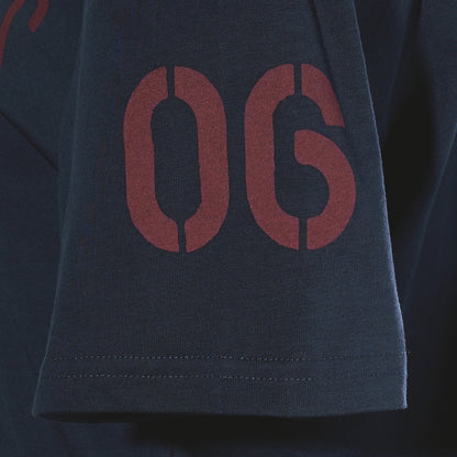 Dark navy sleeve of a Sea Bags Sailing Team T-Shirt featuring the maroon stencil-style numbers “06.”