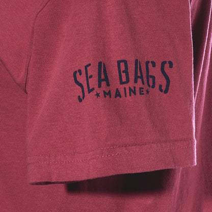 Dark maroon sleeve of an East Coast Shark T-shirt featuring nautical branding that reads “SEA BAGS” above “MAINE,” flanked by two stars.