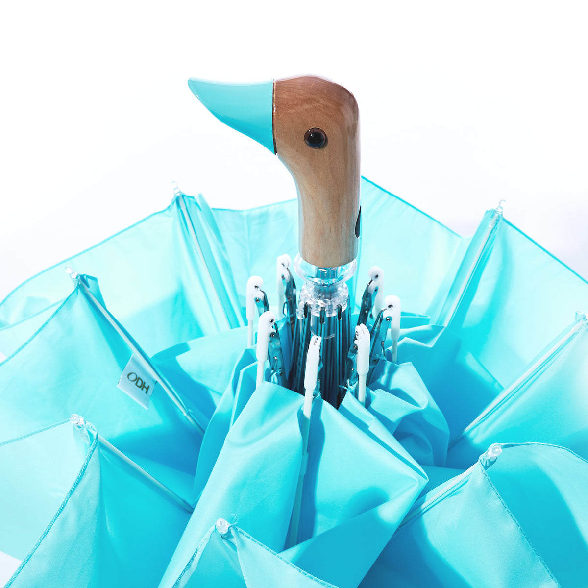 The Original Duck Head Umbrella - Popsicle Blue by ODH Limited t/a Original Duckhead, crafted from recycled plastic and featuring a distinctive duck head-shaped handle, is partially opened against a white background.