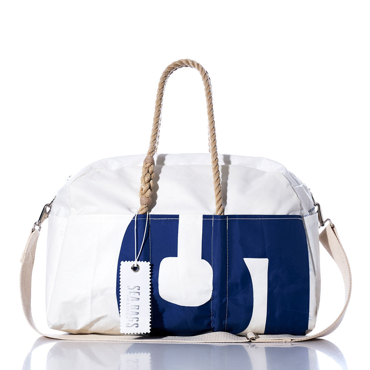 The Vintage 58 Weekender by Sea Bags features a white and navy blue design with rope handles, a cream shoulder strap, and the signature “Sea Bags” tag—making it the perfect getaway bag for any adventure. by Sea Bags