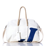 The Vintage J70 Weekender by Sea Bags is a white duffel bag featuring rope handles, a beige shoulder strap, and a bold blue letter J on the front. Ideal as a weekender or getaway bag, it includes a white SEABAGS tag hanging from one handle. by Sea Bags