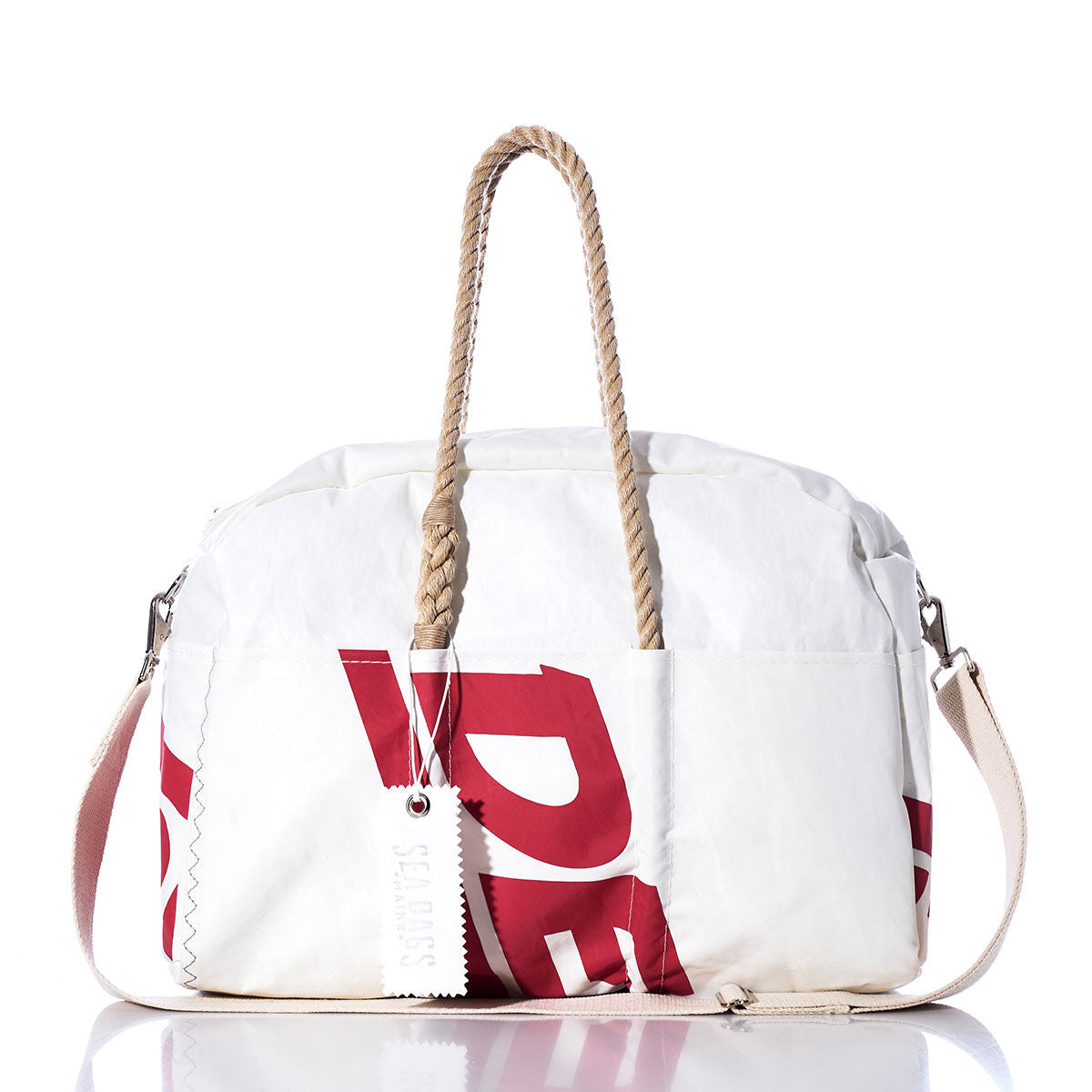 The Sea Bags Vintage Ideal18 Weekender is a white duffel bag featuring bold red lettering, tan braided handles, a detachable shoulder strap, and a white tag, displayed against a clean white background—making it the perfect stylish companion for your next getaway. by Sea Bags