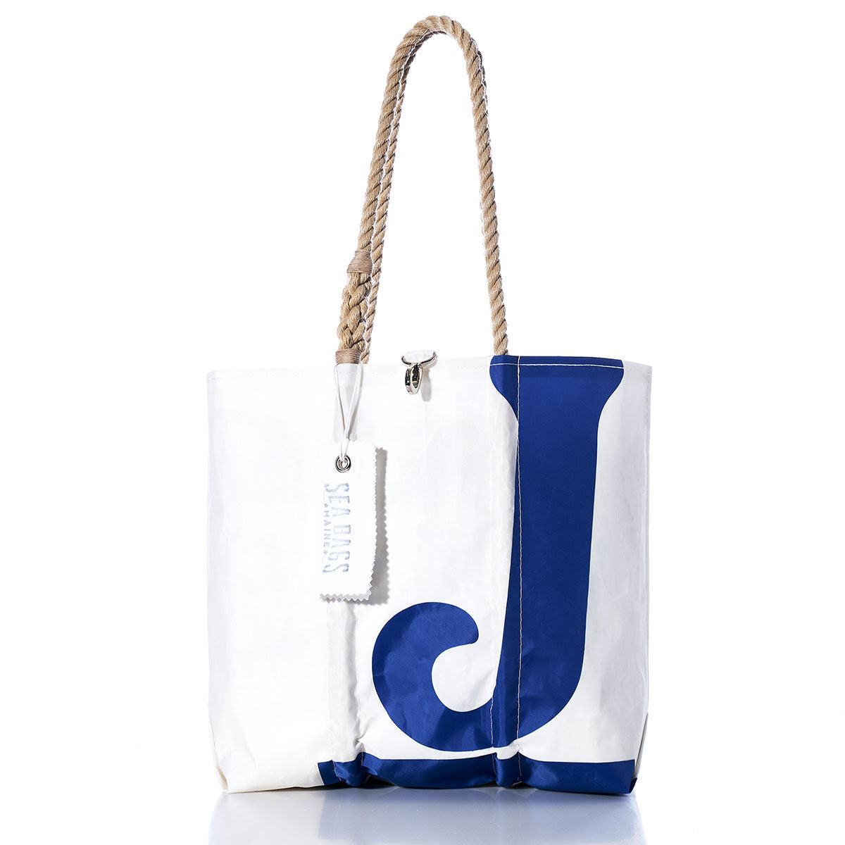 White sailcloth tote bag with sturdy rope handles, featuring a large blue letter J on the front and a white Sea Bags tag near the handle. Handmade in Maine, this bag is part of the Sea Bags Vintage J24 Medium Tote collection. by Sea Bags
